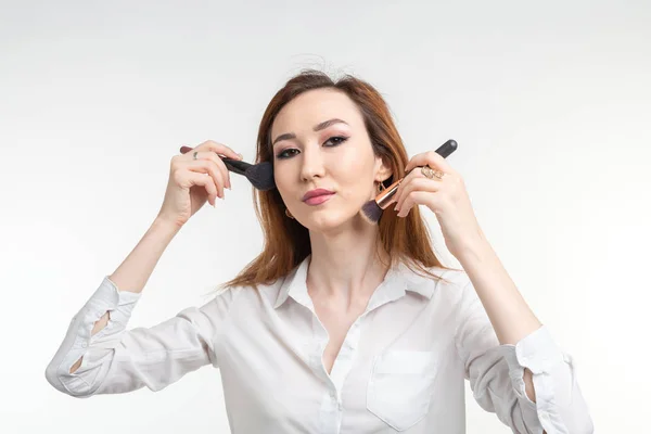 Visagistin, Schönheits- und Kosmetikkonzept - koreanische Visagistin mit Make-up-Pinseln auf weißem Hintergrund — Stockfoto