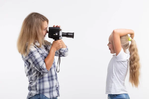 İnsanlar, fotoğraf ve hobi kavram - bir eski moda kamera kullanarak ve beyaz arka plan üzerinde küçük bir kız çekim kadın — Stok fotoğraf