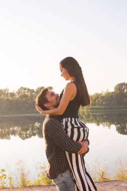 Romantik, insanlar ve yaz kavramı - adam bir kadın göl yakınındaki onun kollarında günbatımında kaldırdı
