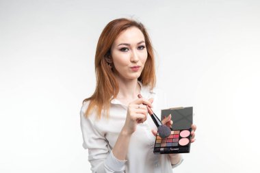 Makyaj sanatçısı, güzellik ve insanlar kavramı - renkli göz gölgeler ve beyaz arka planda fırçalar güzel Koreli Genç kadın holding palet