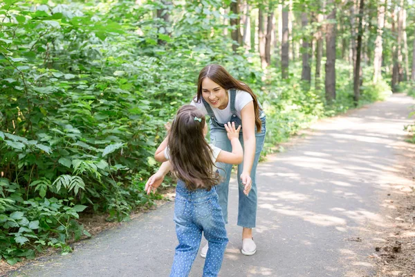 Природа, семья, люди - жизнерадостная маленькая девочка и молодая женщина в красивом лесу. Дочь бежит к матери — стоковое фото
