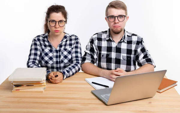 Persone e concetto di istruzione - Due studenti tristi vestiti con camicia a quadri seduti a un tavolo — Foto Stock