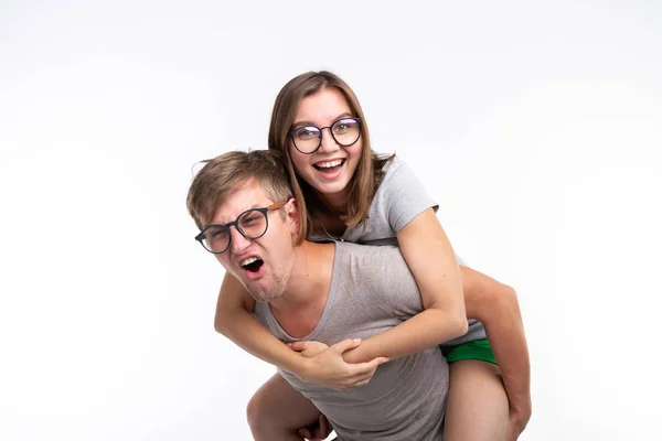 Education, funny people and joke concept - a young woman jumped on a back of man. They are happy — Stock Photo, Image