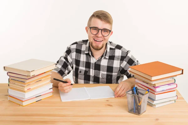 Concepto de conocimiento, estudiante y educación - Guy se sienta a la mesa y toma notas en un cuaderno — Foto de Stock