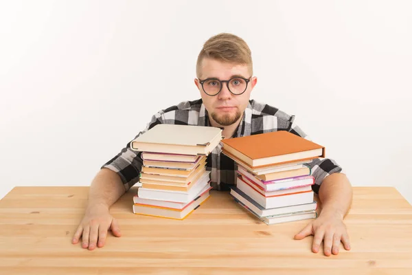 Personas, examen y concepto de educación - Estudiante cansado y cansado vestido con camisa a cuadros sentado en la mesa de madera con muchos libros — Foto de Stock