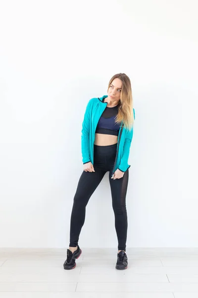 Concept de personnes, de fitness et de sport - Belle femme en forme vêtue de vêtements de sport posant sur fond blanc — Photo