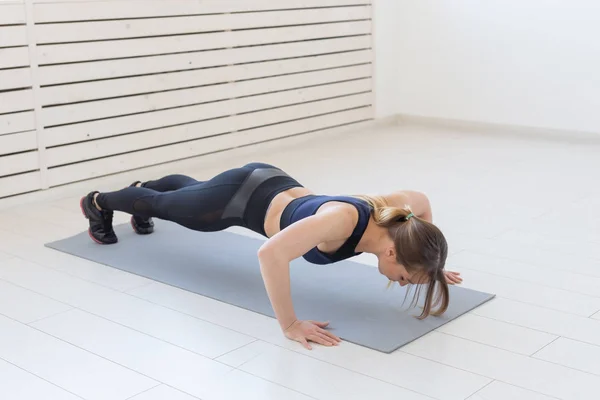 Gente, sano y deportivo concepto- Joven mujer atractiva deportiva haciendo flexiones —  Fotos de Stock