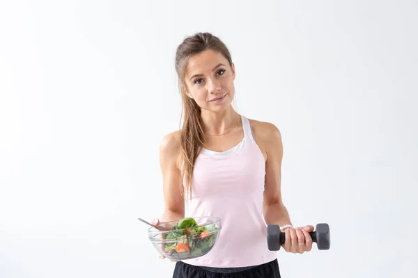 Esporte, estilo de vida são, conceito de pessoas - mulher morena jovem com salada e um halteres. Ela está sorrindo e desfrutando do estilo de vida saudável — Fotografia de Stock