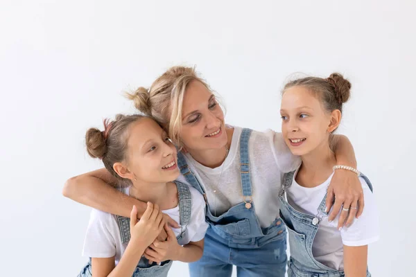 Concepto de personas, familia e hijos - retrato de una madre encantadora abrazando a sus hijas gemelas sobre fondo blanco —  Fotos de Stock