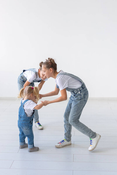 people, family and children concept - twin sisters with their baby sister in hands