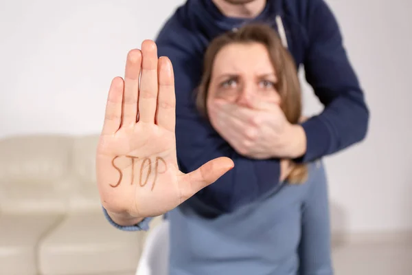 Las personas, la violencia doméstica y el concepto de abuso - Mujer muestra dejar de abusar de signo sobre los antecedentes de los hombres. Hombre cubre su boca con su mano — Foto de Stock