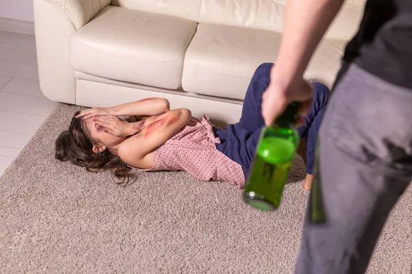 Krajowych przemocy, alkoholu i wykorzystywania koncepcji - pijany człowiek z butelki nadużywa jego żona na podłodze — Zdjęcie stockowe
