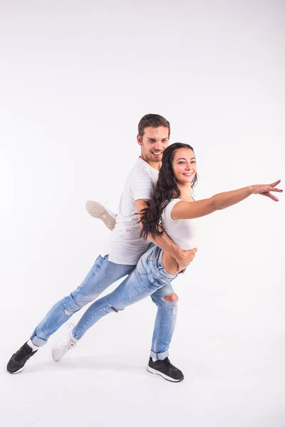 Pareja joven bailando baile social bachata, merengue, salsa, kizomba. Dos pose elegancia en habitación blanca . — Foto de Stock