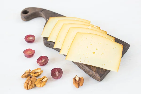 Fresh products. Sliced cheese with grapes and nuts on rustic table.