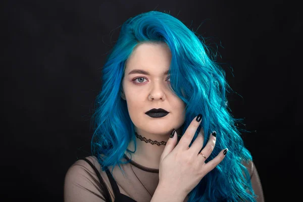Люди та концепція моди - Молода та приваблива жінка з чорною помадою та синім волоссям, що позує на чорному тлі — стокове фото