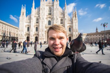 Kış seyahat, tatil ve kuşlar kavramı - selfie güvercinler yakınındaki Milan Katedrali Duomo di Milano, İtalya ile alarak genç komik adam.