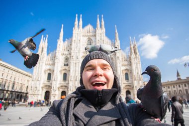 Kış seyahat, tatil ve kuşlar kavramı - selfie güvercinler yakınındaki Milan Katedrali Duomo di Milano, İtalya ile alarak genç komik adam.