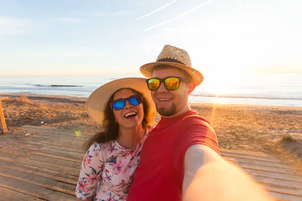 Cestování, léto a dovolená koncept - krásný pár pořizování selfie na pláži — Stock fotografie