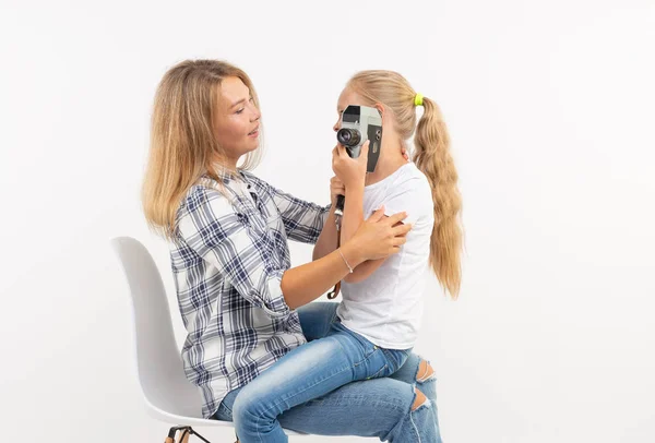 Foto, fotograf a retro fotoaparát koncept - mladá žena a její dcera pomocí vinobraní fotoaparát na bílém pozadí — Stock fotografie