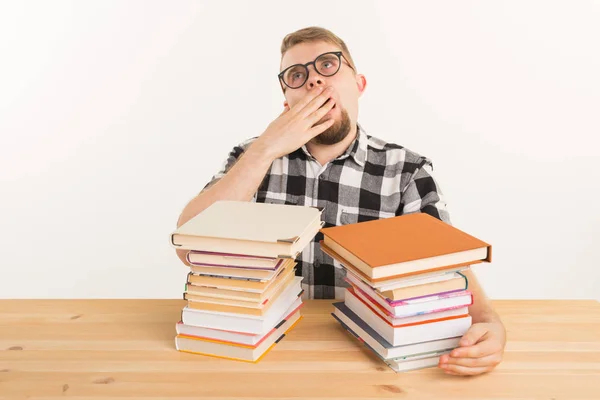 Personas, examen y concepto de educación - Estudiante cansado y cansado vestido con camisa a cuadros sentado en la mesa de madera con muchos libros — Foto de Stock