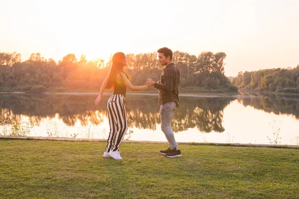 Romantic, social dance and people concept - young couple dancing bachata on the background of sunset