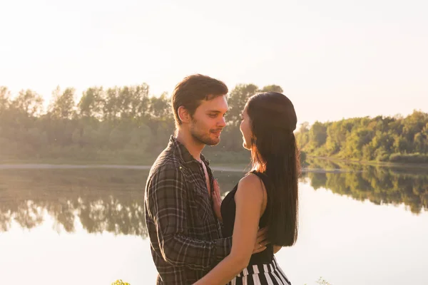 Pessoas, amor e conceito de natureza - Jovem mulher bonita e homem bonito abraçando uns aos outros sobre fundo de água — Fotografia de Stock