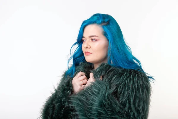 Proteção animal, moda e conceito de pessoas - menina bonita vestida com casaco de pele artificial com cabelo azul em pé sobre fundo branco — Fotografia de Stock