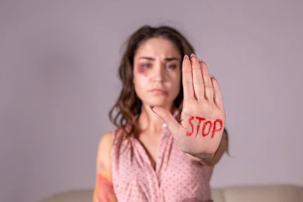 Domestic violence, protesting and people concept - brunette woman expressing denial with STOP on her hand on grey room — Stock Photo, Image