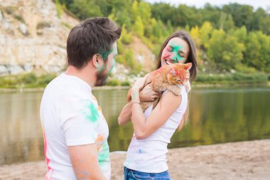 Evde beslenen hayvan, yaz turizm, festival holi ve doğa kavramı - komik erkek ve kadın ile kedi doğal zemin üzerine