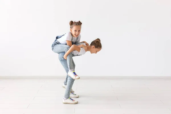 Concepto de familia y amor - feliz chica gemela dando paseo a cuestas a su hermana riendo — Foto de Stock