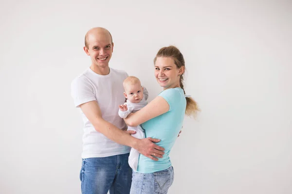 Orgullosa madre y padre sonriendo a su hija recién nacida sobre fondo blanco — Foto de Stock