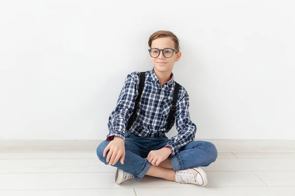 Teenager, Kinder und Modekonzept - niedliches Kind mit Brille auf dem Boden vor weißem Hintergrund — Stockfoto