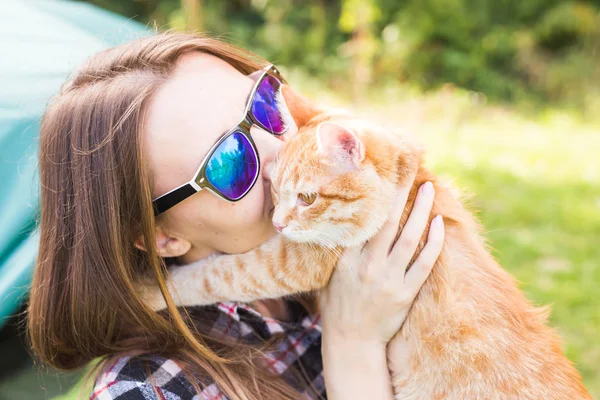 People, tourism and nature concept - Woman in sunglasses holding a cat sitting near the tent — Stock Photo, Image