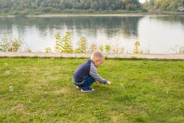Дети и концепция природы - Мальчик пытается поймать мыльные пузыри — стоковое фото