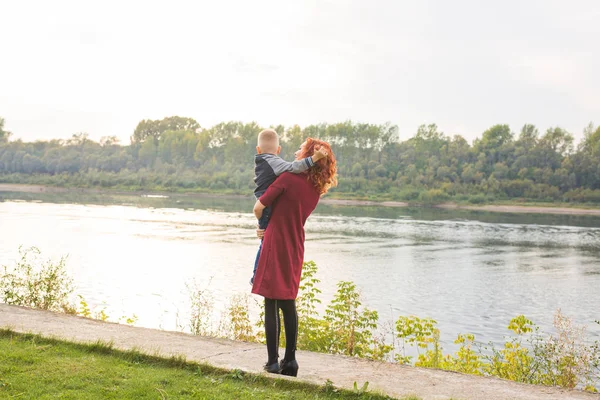 Mutterschafts- und Kinderkonzept - junge Mutter mit Sohn im Arm in der Nähe des Flusses — Stockfoto
