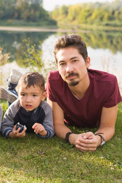 Bambini, genitorialità e natura - Padre e figlio sdraiati sull'erba — Foto Stock