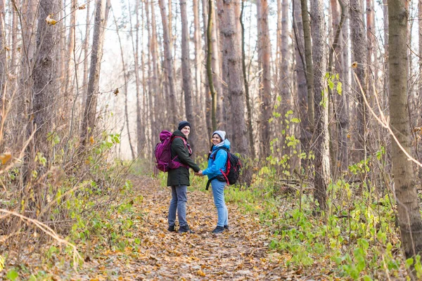 Viagens, turismo, caminhada e conceito de natureza - Turistas caminhando no parque com mochila vestida com jaquetas azuis e pretas — Fotografia de Stock