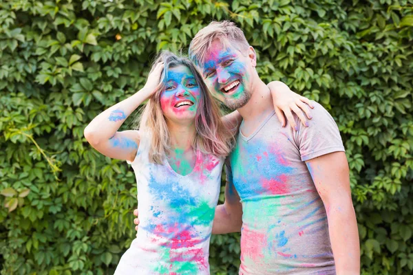 Amizade, festival de holi, conceito de pessoas - jovem casal brincando com cores no festival de holi — Fotografia de Stock