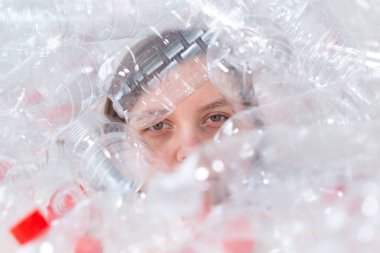 Susuz kalmış hasta kadın plastik şişeyığının içinde yatıyor. Çevre kirliliği sorunu. Doğaçöp çevre koruma konsepti durdurun