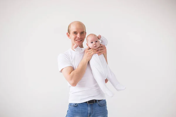 Paternidad, paternidad y concepto de bebé: un padre calvo feliz y sonriente que sostiene a una niña pequeña sobre un fondo blanco — Foto de Stock