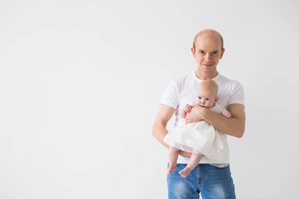 Concepto de paternidad, familia y paternidad: padre calvo abrazando a su pequeña hija bebé sobre un fondo blanco con espacio para copiar — Foto de Stock