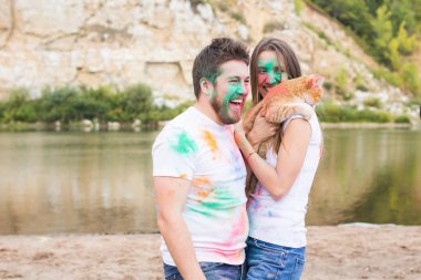 Festival holi, tatil, turizm, evde beslenen hayvan ve doğa kavramı - kadın ve erkek kedi ile portre çok renkli toz kaplı.