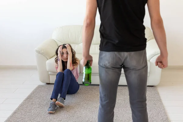 Domestic violence, alcoholic and abuse concept - drunk man with bottle abusing his wife lying on the floor — Stock Photo, Image