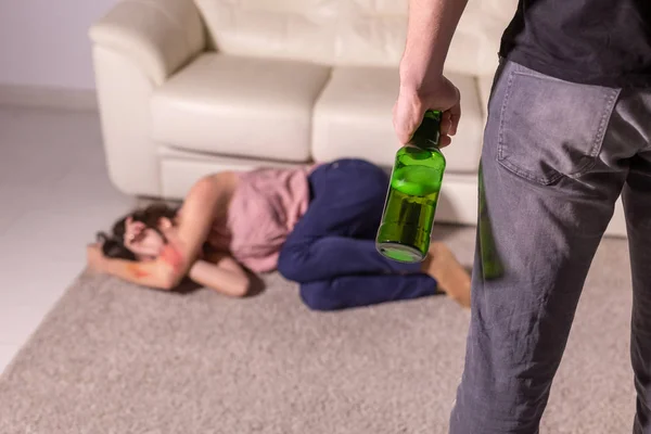 Alcoholismo, abuso y violencia doméstica - Mujer acostada en el suelo, temerosa de los hombres con botella —  Fotos de Stock