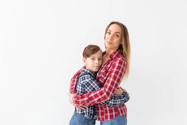 Conceito de família, moda e dia da mãe - menino adolescente abraçando sua mãe no fundo branco com espaço de cópia — Fotografia de Stock