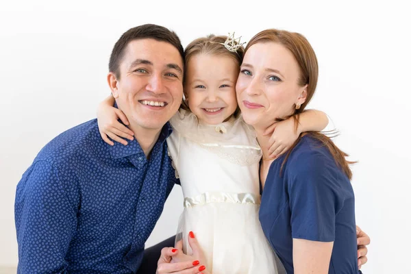Concepto de familia, padres e hijos - Familia encantadora con una pequeña hija linda sobre fondo blanco — Foto de Stock