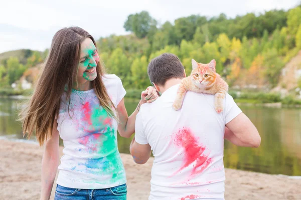 축제 holi, 관광 및 자연 개념-여자와 고양이 함께 남자의 초상화 덮여 멀티 컬러 먼지 — 스톡 사진