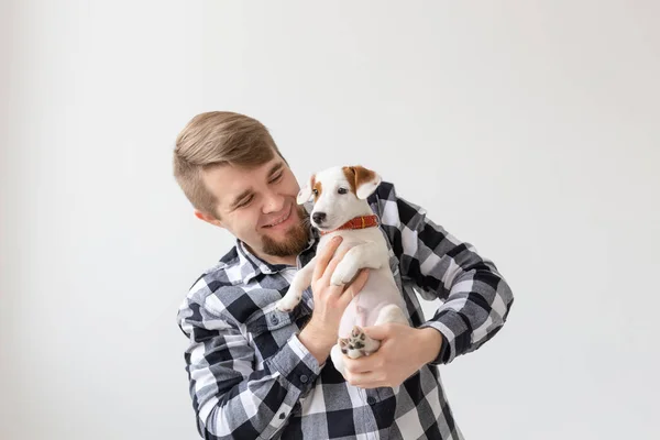 Concepto de personas, mascotas y perros - joven abrazando divertido cachorro sobre fondo blanco — Foto de Stock
