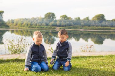 Çocuk ve doğa kavramı - çim üzerinde doğa arka plan üzerinde oturan iki kardeş