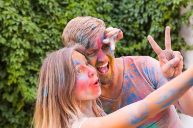 Tatil, bayram ve insanlar kavramı - kadın ve erkek selfie bush backgrund alarak boyalı yüzler ile